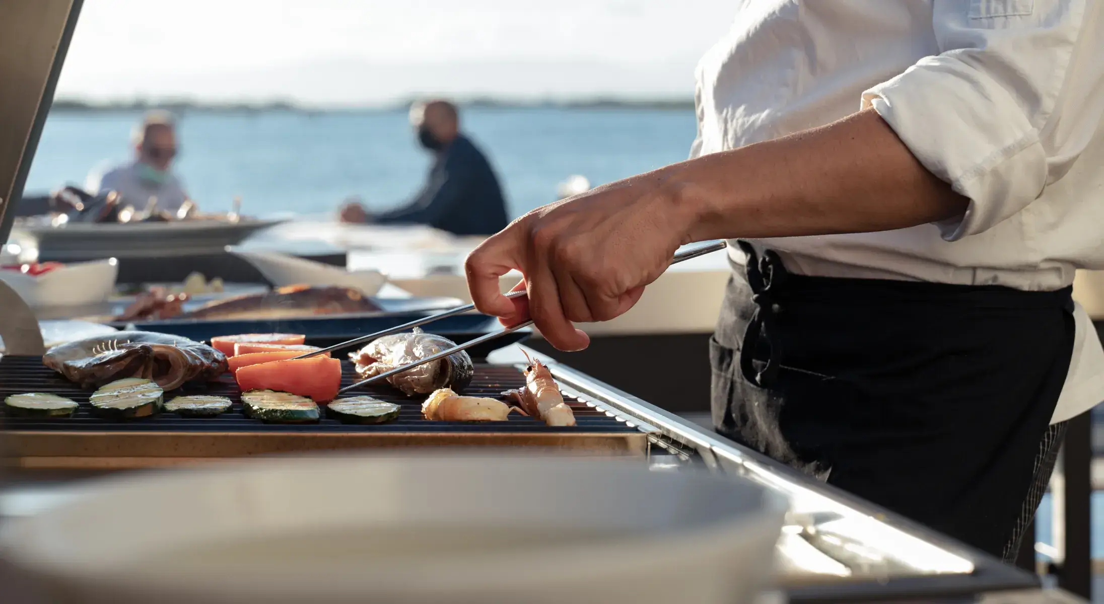 Preparazione di pesce e verdure su barbecue Fògher